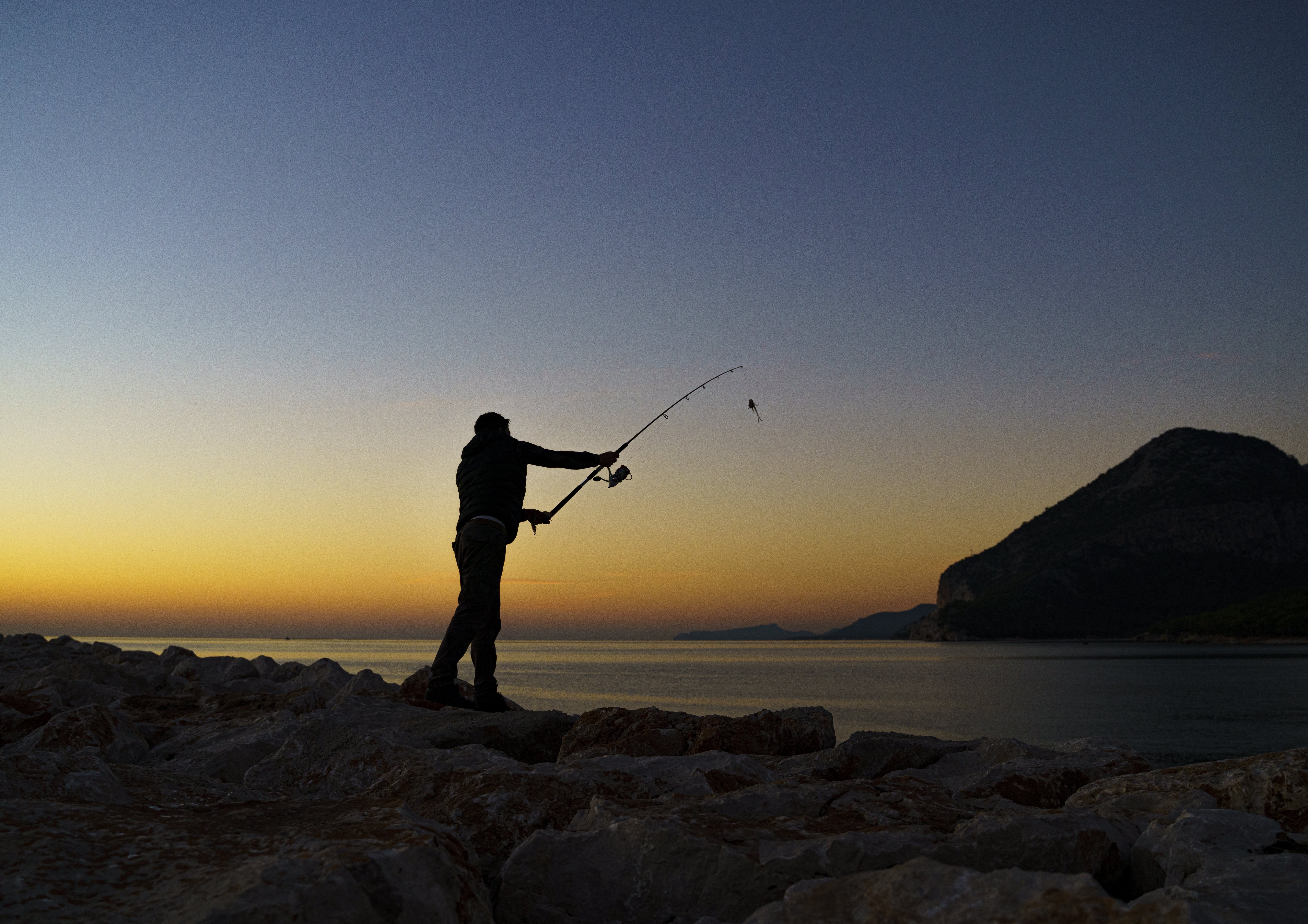 Silhouette casting a fishing rod